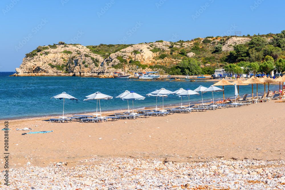 Sun loungers with umbrellas on sandy Kolymbia beach. Rhodes island, Greece