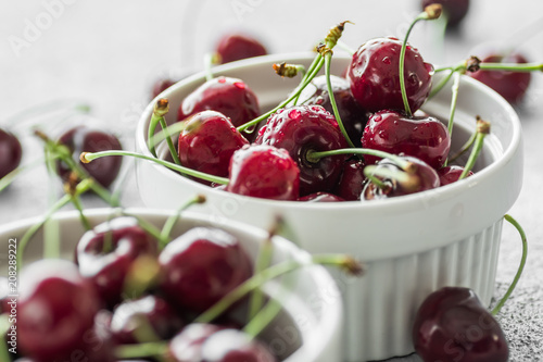 Fresh summer cherries in white bowls on grey background