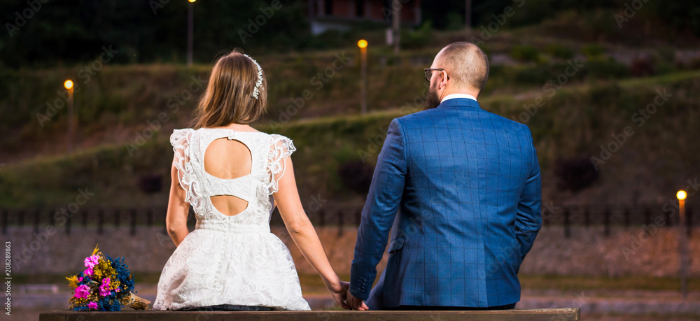 Obraz premium Bride and groom sitting by a lake at night