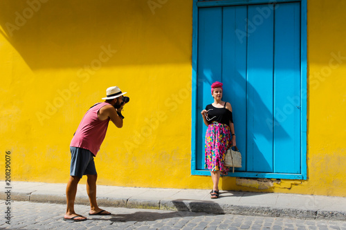 Man taking a photo of a girl against a yellow wall © creativefamily
