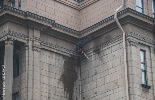 Man working with pressure washer on the wall of the building.