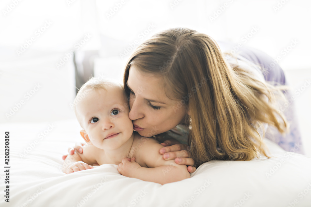 Happy mother with baby lying on bed at home