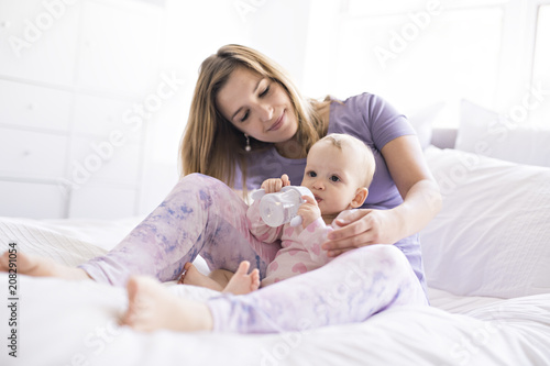 Happy mother with baby lying on bed at home photo