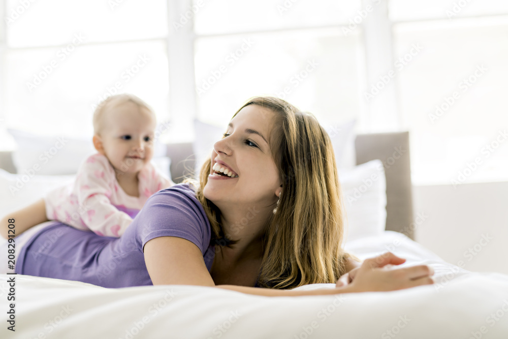 Happy mother with baby lying on bed at home Happy mother with baby lying on bed at home