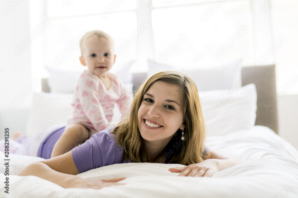 Happy mother with baby lying on bed at home Happy mother with baby lying on bed at home