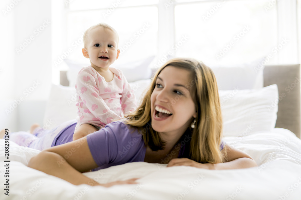 Happy mother with baby lying on bed at home Happy mother with baby lying on bed at home