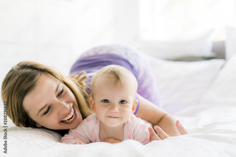 Happy mother with baby lying on bed at home Happy mother with baby lying on bed at home