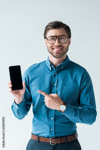 Wallpaper Mural happy young man holding smartphone and pointing at blank screen isolated on white Torontodigital.ca