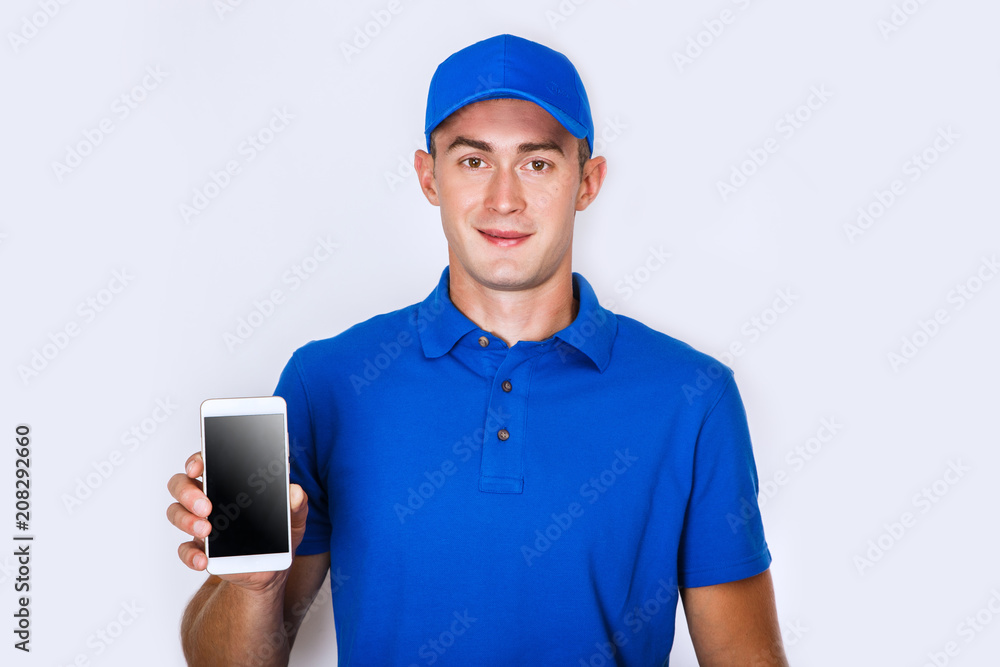 Happy courier with phone. looking at camera. isolated gray background. Studio shoot Happy courier with phone. looking at camera. isolated gray background. Studio shoot