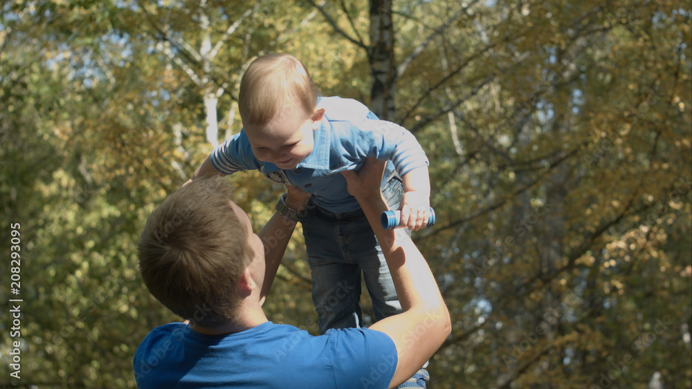Dad tosses son into the air in an autumn Park. Happy family. Dad tosses son into the air in an autumn Park. Happy family.