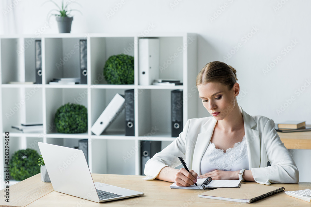 focused young businesswoman making notes during work at office focused young businesswoman making notes during work at office