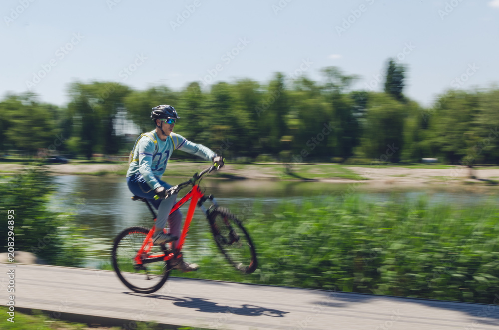 A cyclist in a helmet rides a bicycle path, motion blur