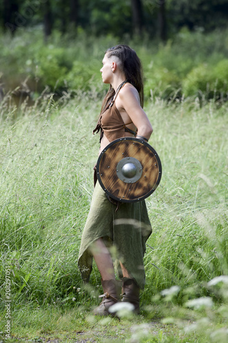 beautiful Celtic shieldmaiden in the field with shield