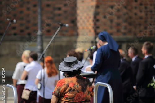Stara kobieta w kapeluszu słucha muzyki i śpiewu chóru.