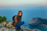 woman traveler sitting on a cliff cliff, tourism concept