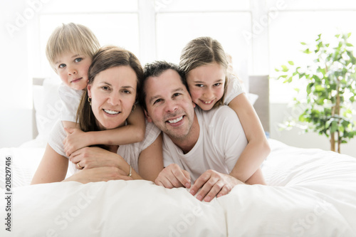 Family of four having fun on the bed at home