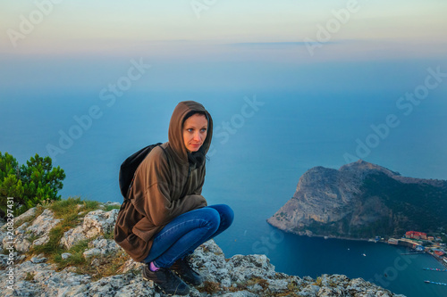 woman traveler sitting on a cliff cliff, tourism concept