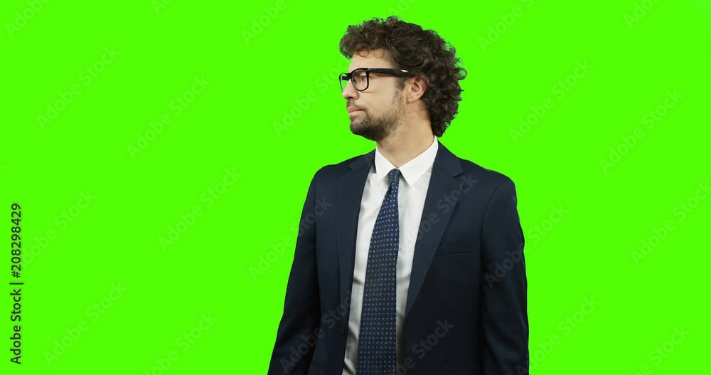 Angry serious Caucasian businessman in the glasses, suit and tie looking at the hand watch and being nervous as waiting for somebody. Green screen. Chroma key. Angry serious Caucasian businessman in the glasses, suit and tie looking at the hand watch and being nervous as waiting for somebody. Green screen. Chroma key.