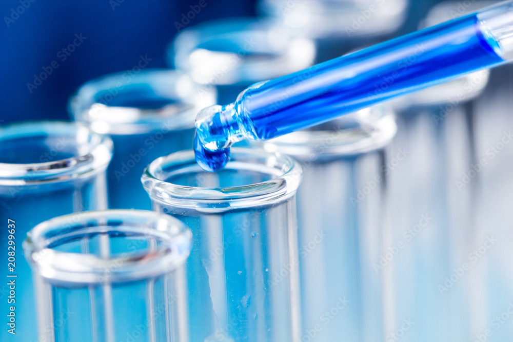 Pipette with blue liquid water drop fall in test tube in laboratory. Pipette with blue liquid water drop fall in test tube in laboratory.