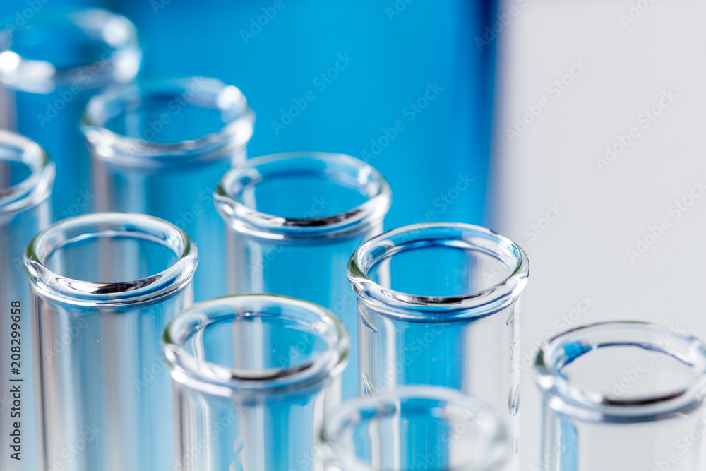 Glass test tubes on blue background in laboratory. Glass test tubes on blue background in laboratory.