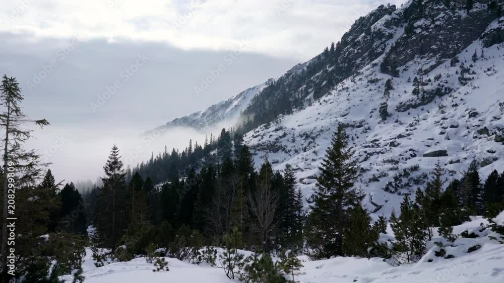 Winter hiking in rocky mountains landscape covered in snow during cold weather on sunny day Winter hiking in rocky mountains landscape covered in snow during cold weather on sunny day