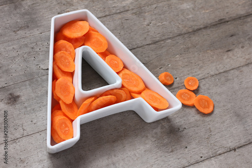 Vitamin A in food concept. Plate in the shape of the letter A with sliced fresh carrots.