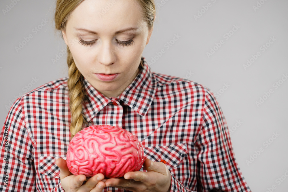 Woman thinking and holding fake brain Woman thinking and holding fake brain