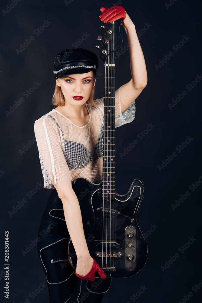 Girl in leather cap with guitar Rock and roll Rock woman with blonde hair on black background Cool look of sexy girl play music on electric guitar Fashion model with stylish hairdo Guitar fun