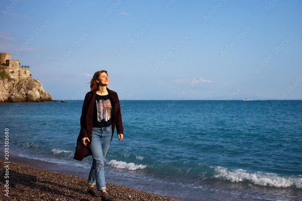 Young girl goes to the beach near the sea in the spring. Amalfi, Italy