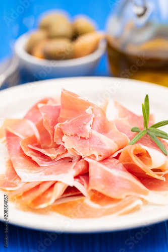 prosciutto on dish with olive oil and olives