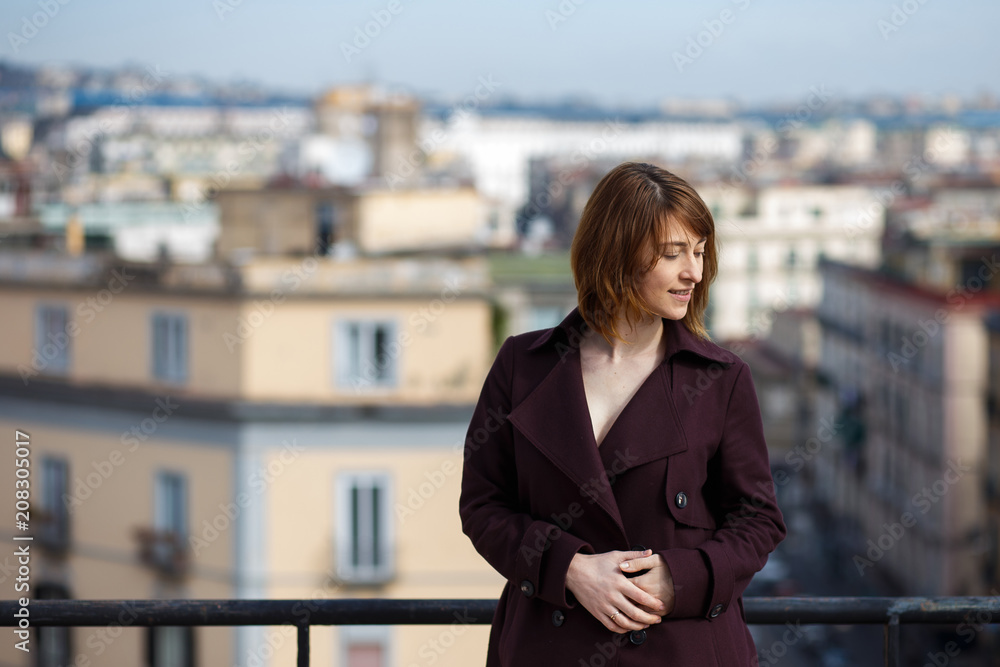 portrait of an attractive woman looking down in the balkony in street background Naples, Italy