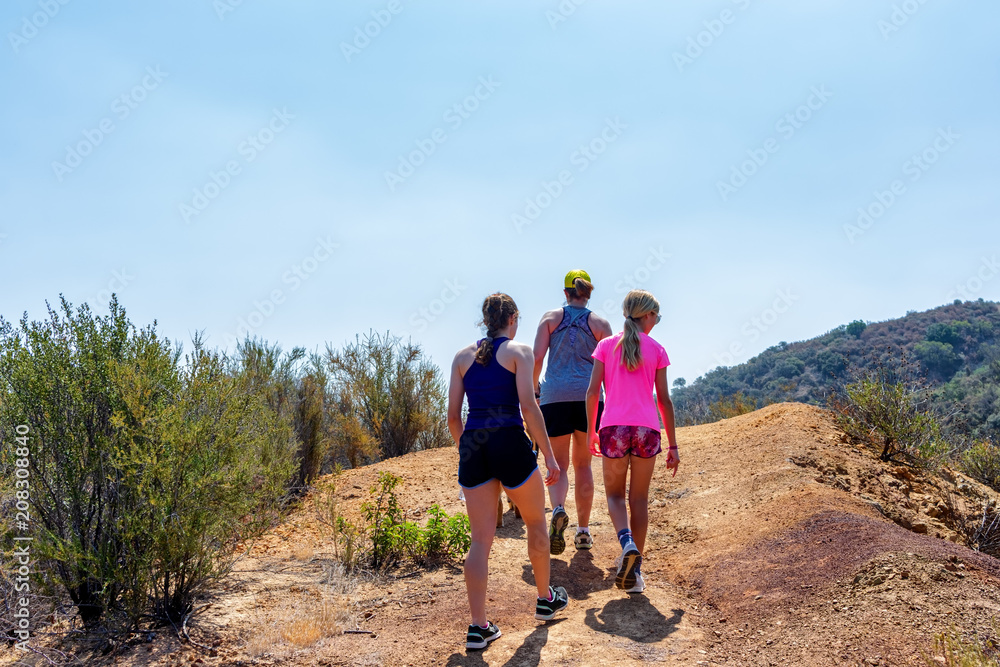Family hiking reaches the top of hill on summer morning in California
