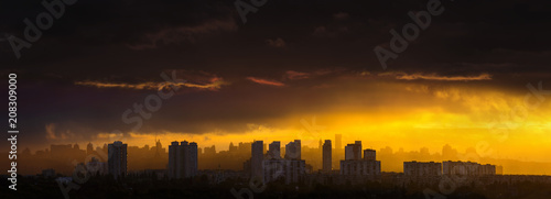 Awesome stunning evening sunset in dramatic sky. Panoramic cityscape big town silhouette in incredibly bright sunshine through hard rain. View to downtown from left bank Dnipro river. Kyiv. Ukraine.