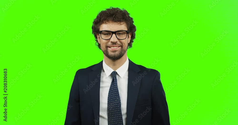 Attractive smiled man in glasses, suit and tie doing victory gesture with fingers on the chroma key background. Green screen. Attractive smiled man in glasses, suit and tie doing victory gesture with fingers on the chroma key background. Green screen.