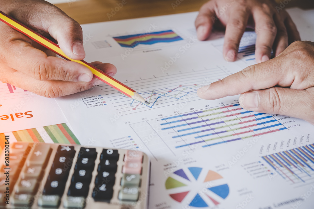 male hands pointing at turnover graph while discussing it on wooden desk in office. group support concept. male hands pointing at turnover graph while discussing it on wooden desk in office. group support concept.