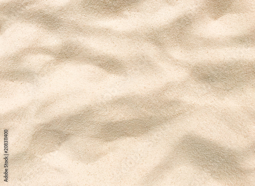 Beach sand texture. Beautiful sandy background with golden and white grains. Wavy and dry sand