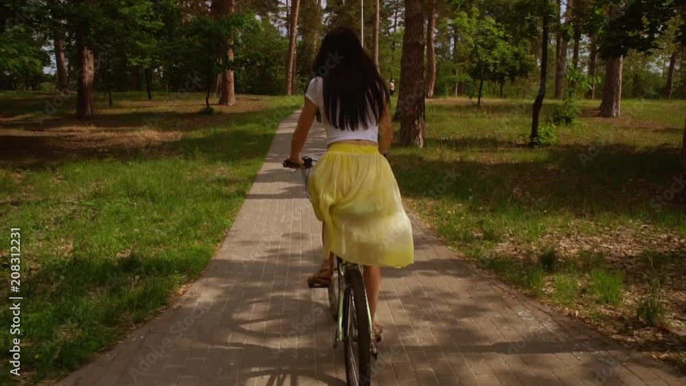 slow motion back view woman wearing bright fluttering skirt riding on ...