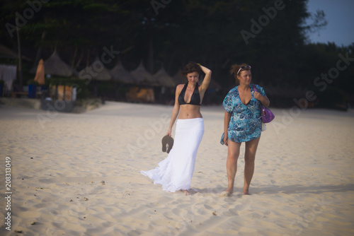 two women walk along the ocean in summer photo