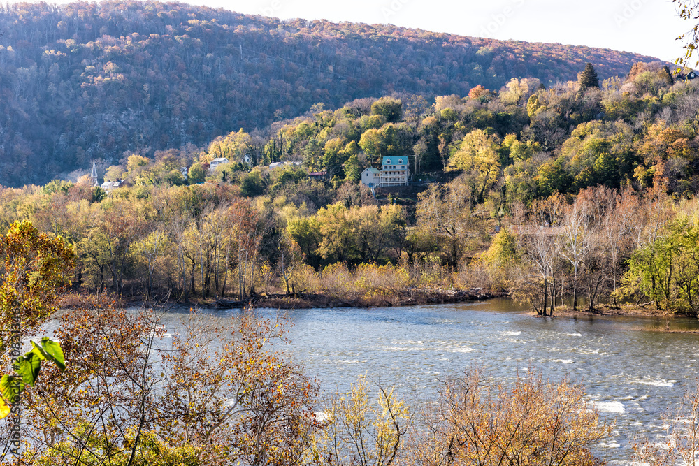 Harper's Ferry blue Potomac River riverside with colorful orange yellow foliage fall autumn by small village town in West Virginia, WV, house on hill mountain