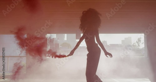 Wallpaper Mural Silhouette young woman dancing with colorful red smoke bomb in parking garage Torontodigital.ca