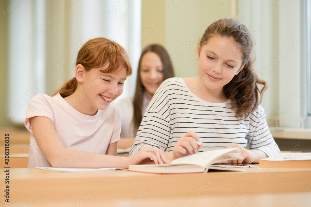 3 student girls are sitting at a Desk 3 student girls are sitting at a Desk