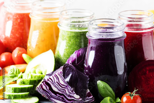 Food and drinks, selection of healthy and useful colorful vegetable juices and smoothies with chia and flax seeds in glass bottles, set on gray background, selective focus