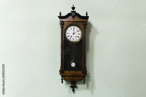 Old wooden pendulum hanging on a wall on blue background.