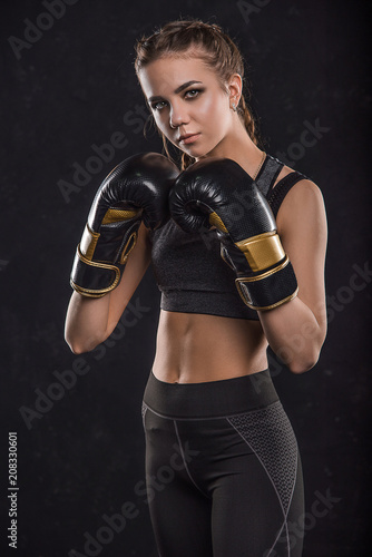  Beautiful sportswoman in boxing gloves on a black background
