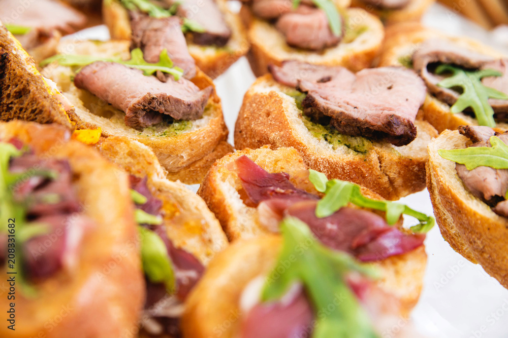 sandwiches with meat and pesto sauce on a banquet table sandwiches with meat and pesto sauce on a banquet table