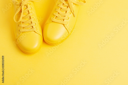 Pair of yellow shoes on yellow background. Trendy summer color, monochrome image. Hipster concept. Shot at angle.