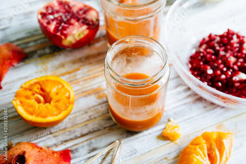 Pomegranate and orange juice is poured on a jar glas. Fruts pomegranate seeds and orange cut n half around,top view over a wooden background