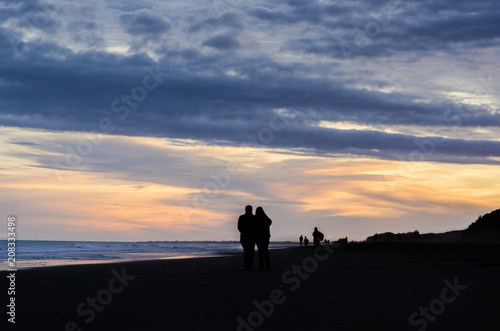 Couple walking in the beach at sunset © Javier