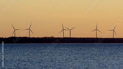 Turbiny wiatrowe na estońskim wybrzeżu Bałtyku, kręcące się z wolna podczas pogodnego, letniego wieczoru