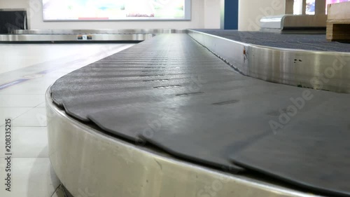 empty conveyor belt moving in arrivals lounge of airport terminal for traveller , passenger or business man 's suitcase